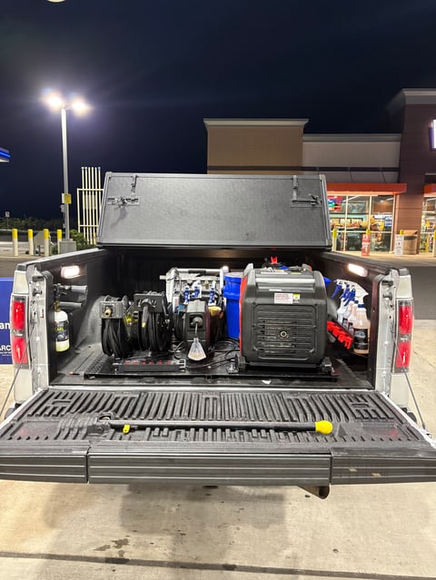 Open truck bed filled with tools and equipment at night in a parking lot