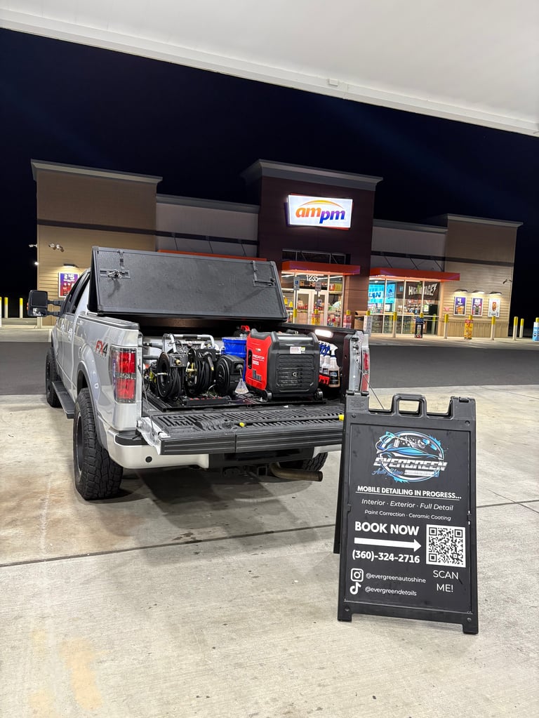 White pickup truck with open bed displaying mobile detailing equipment and signage in parking lot